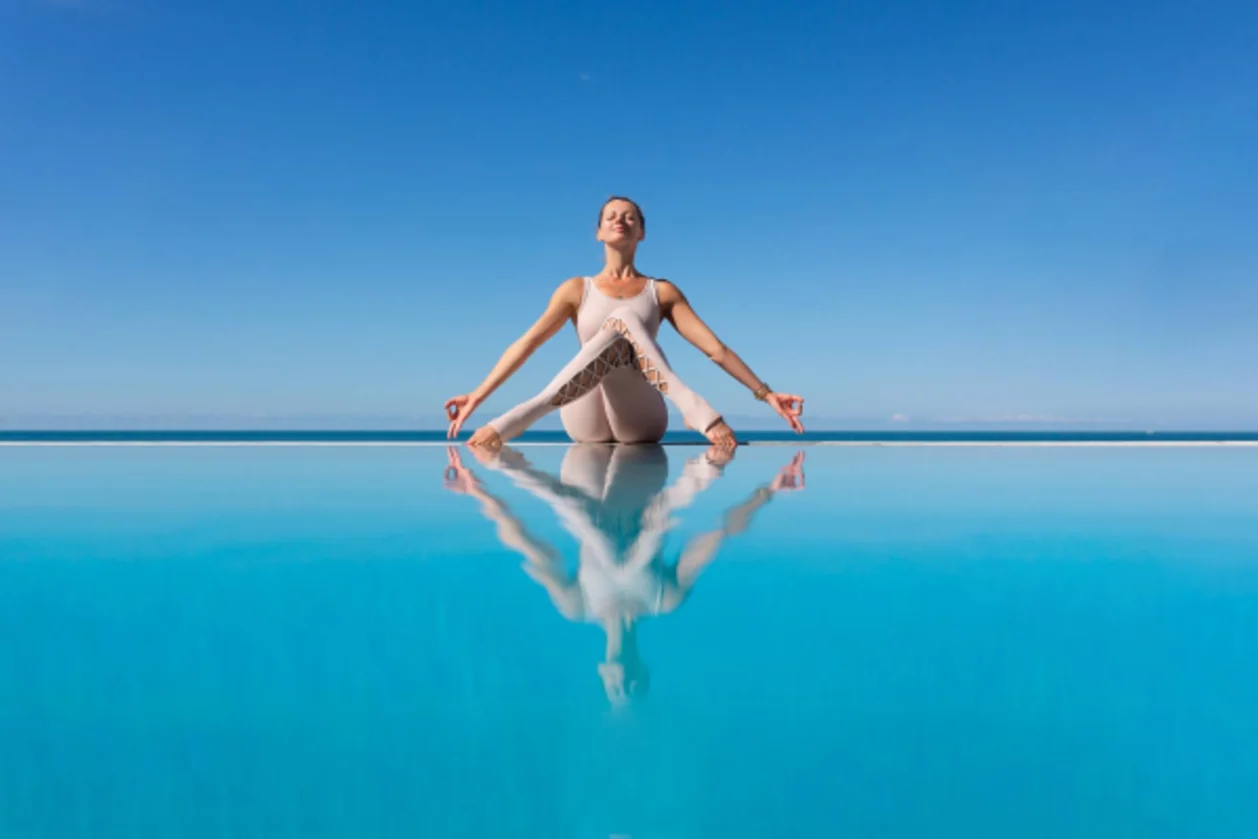 woman doing homukhasana on the edge of infinity pool